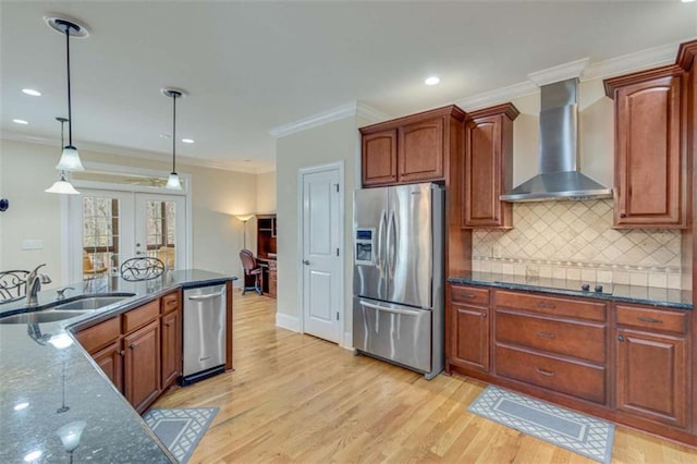 kitchen with stainless steel appliances, hanging light fixtures, french doors, wall chimney range hood, and light wood-type flooring