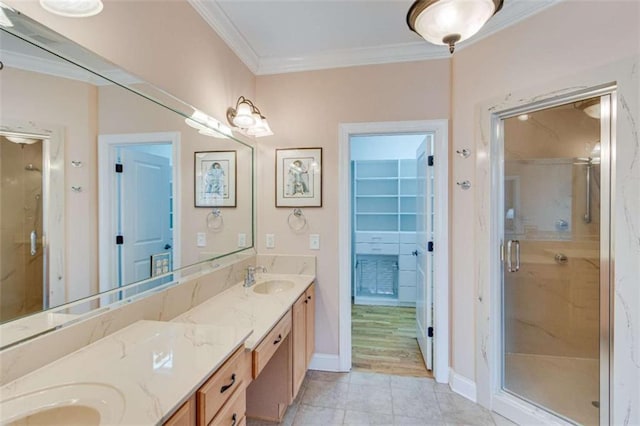 bathroom featuring tile patterned floors, a sink, a shower stall, crown molding, and double vanity