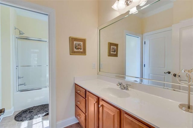 bathroom with combined bath / shower with glass door, vanity, and baseboards