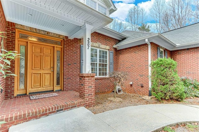 entrance to property with brick siding and roof with shingles