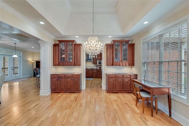 kitchen featuring plenty of natural light, light wood-style flooring, a raised ceiling, and ornamental molding