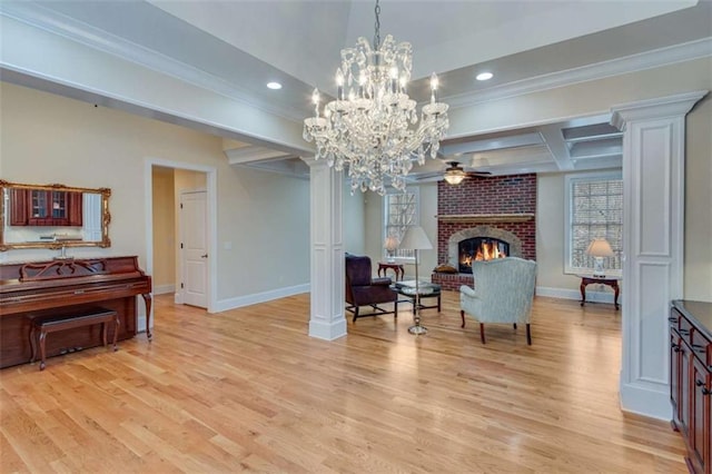 sitting room with beamed ceiling, light wood finished floors, a fireplace, and ceiling fan with notable chandelier