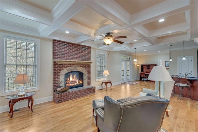 living room featuring beamed ceiling, light wood-style floors, and baseboards