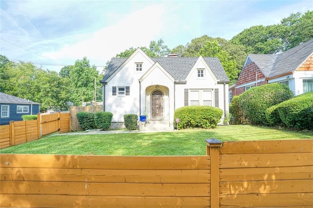 exterior space featuring a front yard, roof with shingles, and fence