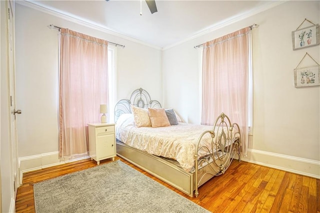 bedroom with baseboards, wood finished floors, a ceiling fan, and crown molding