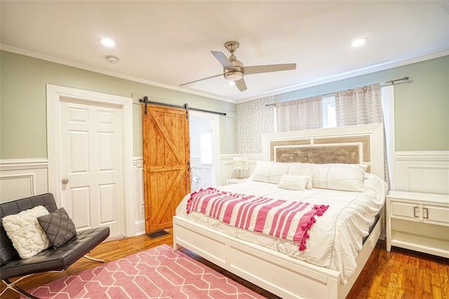 bedroom featuring a barn door, wood finished floors, and crown molding