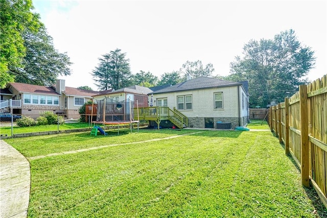 back of house with a lawn, a fenced backyard, a residential view, a trampoline, and stairs