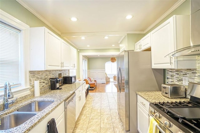 kitchen with white cabinets, crown molding, stainless steel appliances, and a sink