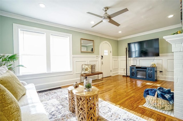 living area with a healthy amount of sunlight, a fireplace, visible vents, and wood finished floors