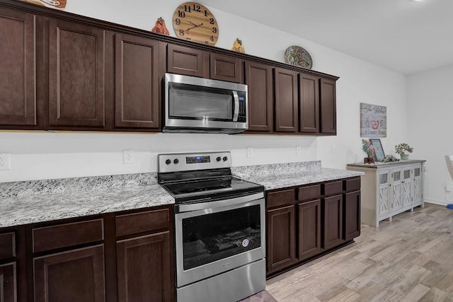 kitchen with appliances with stainless steel finishes, light hardwood / wood-style flooring, dark brown cabinets, and light stone countertops