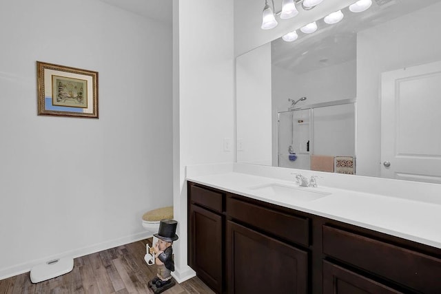 bathroom with hardwood / wood-style floors, a shower, toilet, and vanity