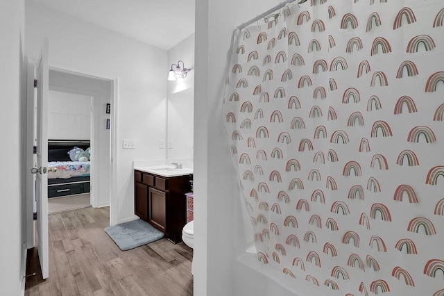 full bathroom with shower / tub combo with curtain, toilet, vanity, and hardwood / wood-style flooring