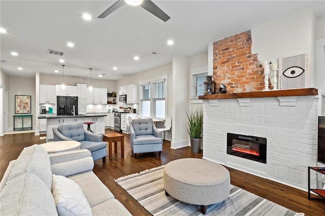 living area featuring a fireplace, dark wood finished floors, visible vents, and recessed lighting