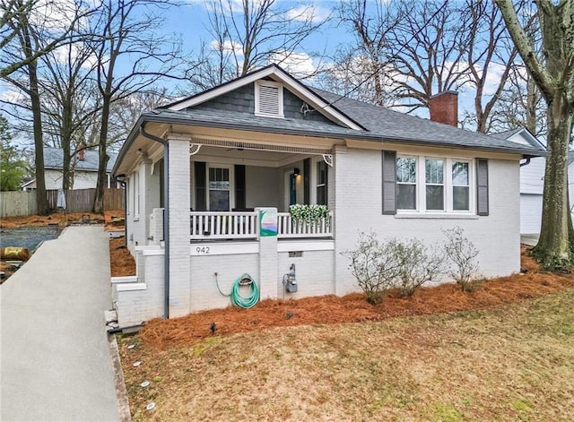 bungalow-style house featuring crawl space, a chimney, a porch, and brick siding