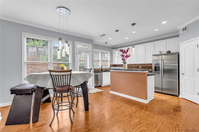 947 Summer Forest Dr, Suwanee, GA 30024 - kitchen with appliances with stainless steel finishes, ornamental molding, a center island, dark countertops, and light wood-type flooring