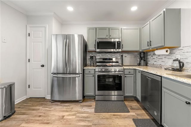 kitchen with stainless steel appliances, decorative backsplash, gray cabinetry, and ornamental molding