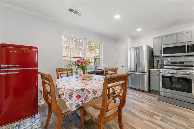 dining area with light wood-style flooring, recessed lighting, visible vents, and crown molding