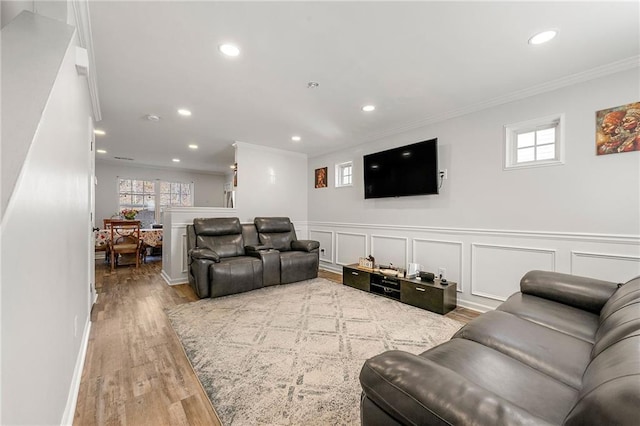 living area featuring a decorative wall, wood finished floors, a wealth of natural light, and crown molding