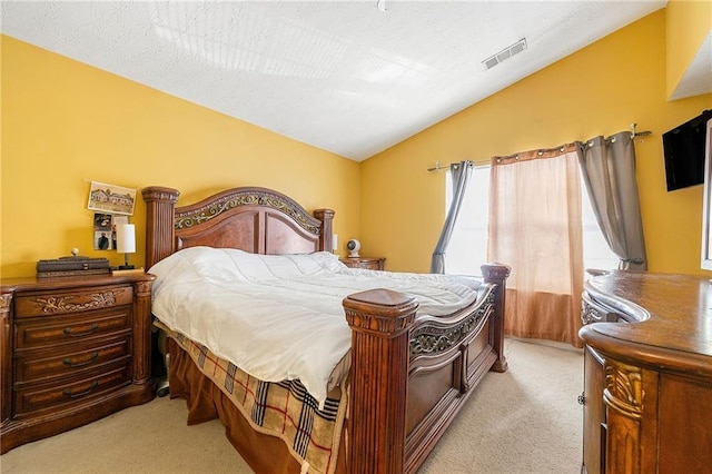 bedroom featuring light colored carpet, visible vents, vaulted ceiling, and a textured ceiling