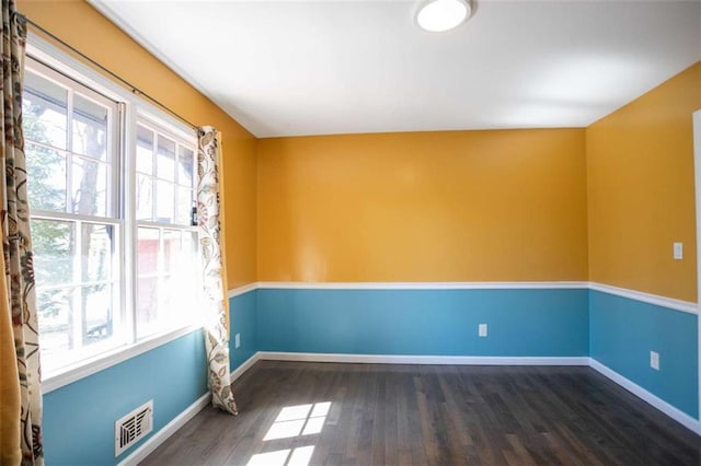 spare room with baseboards, wood finished floors, visible vents, and a healthy amount of sunlight