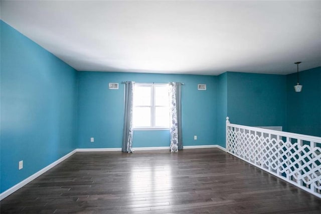 spare room featuring dark wood-type flooring and baseboards