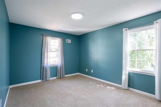 empty room featuring carpet, visible vents, and baseboards