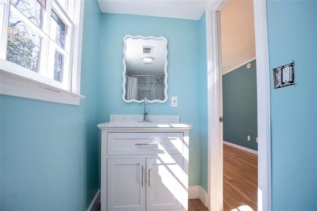 bathroom featuring visible vents, wood finished floors, vanity, and baseboards