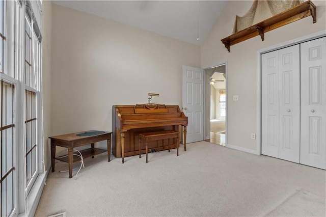 living area with high vaulted ceiling, light carpet, ceiling fan, and baseboards