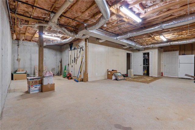unfinished basement with freestanding refrigerator