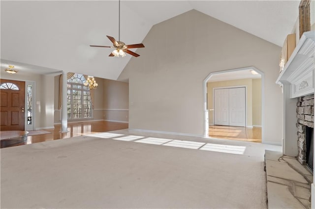 unfurnished living room with high vaulted ceiling, light carpet, a fireplace, and ceiling fan with notable chandelier