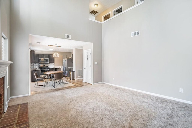 living area with a brick fireplace, light colored carpet, and visible vents