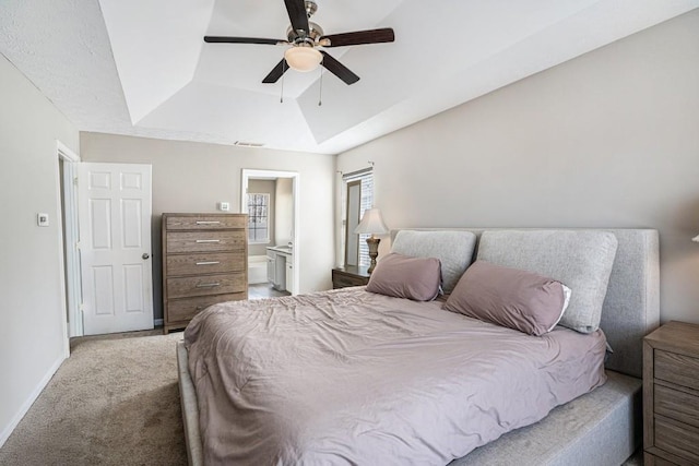 carpeted bedroom featuring visible vents, baseboards, ensuite bath, ceiling fan, and a raised ceiling