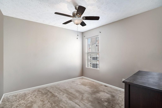 carpeted spare room featuring ceiling fan, baseboards, and a textured ceiling