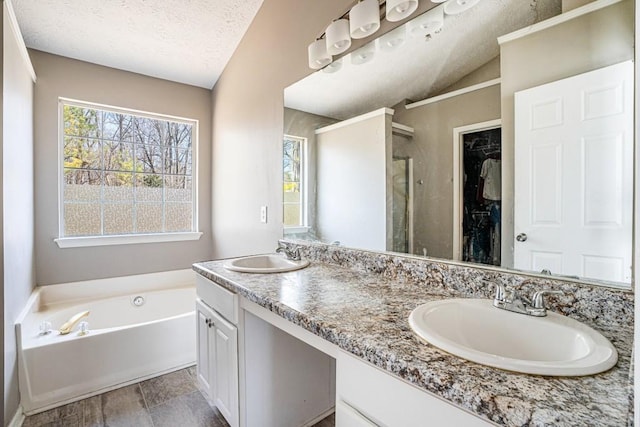 full bath featuring a sink, a textured ceiling, a bath, and a shower stall