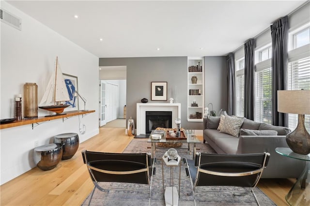 living room featuring built in features and light hardwood / wood-style flooring