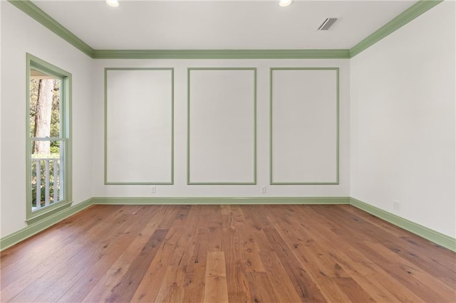 spare room with visible vents, baseboards, wood-type flooring, and ornamental molding