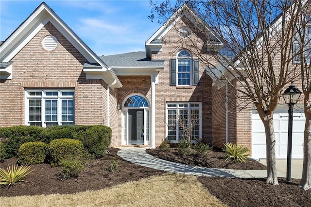 traditional-style house with a garage, brick siding, and driveway