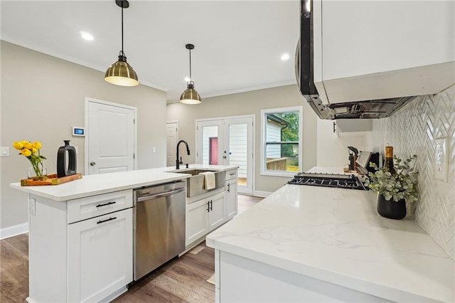 kitchen featuring a sink, exhaust hood, a kitchen island with sink, white cabinetry, and stainless steel dishwasher