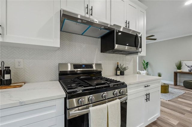 kitchen with under cabinet range hood, stainless steel appliances, tasteful backsplash, and white cabinetry