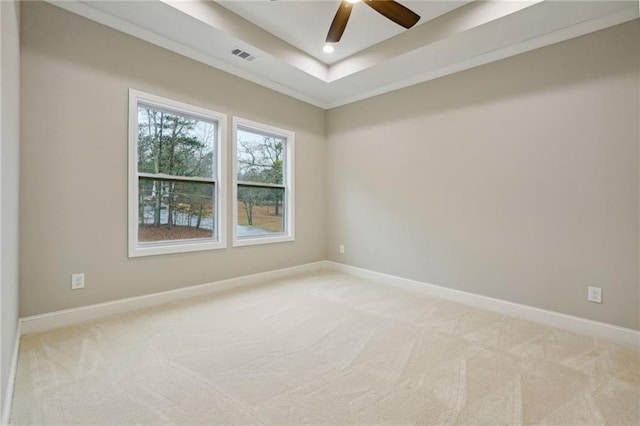 spare room featuring visible vents, baseboards, a raised ceiling, ceiling fan, and light carpet