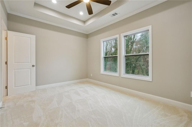 unfurnished room with a ceiling fan, a tray ceiling, baseboards, visible vents, and light carpet