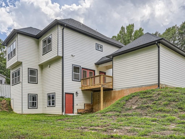 rear view of house with a wooden deck and a lawn