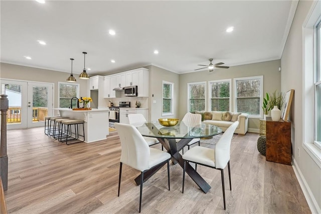 dining space with crown molding, a wealth of natural light, french doors, and a ceiling fan