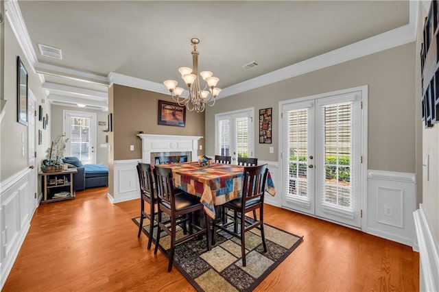 2677 Sardis Chase Ct, Buford, GA 30519 - dining area with crown molding, a chandelier, light wood-style flooring, a decorative wall, and wainscoting