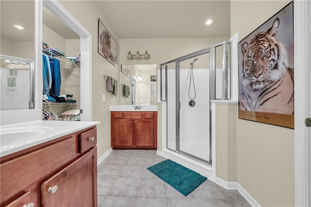 2677 Sardis Chase Ct, Buford, GA 30519 - bathroom featuring a shower stall, two vanities, a walk in closet, tile patterned flooring, and baseboards