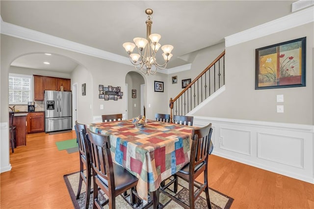 2677 Sardis Chase Ct, Buford, GA 30519 - dining room with arched walkways, light wood-style flooring, a chandelier, wainscoting, and ornamental molding