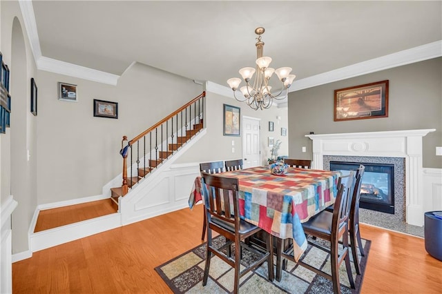 2677 Sardis Chase Ct, Buford, GA 30519 - dining room featuring light wood finished floors, ornamental molding, stairs, a chandelier, and a glass covered fireplace
