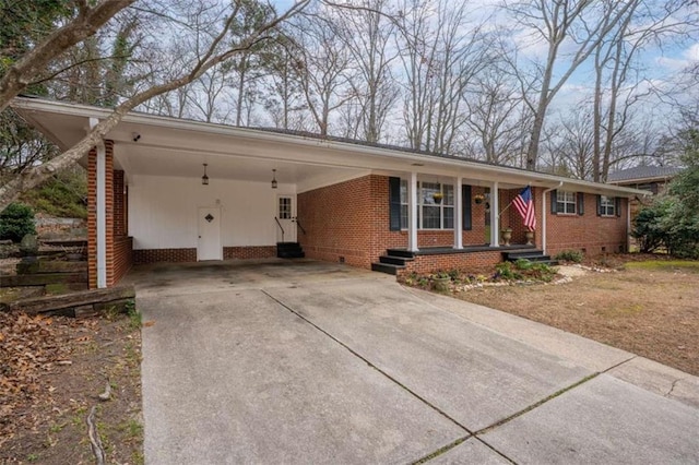 ranch-style home featuring a carport, entry steps, concrete driveway, and brick siding