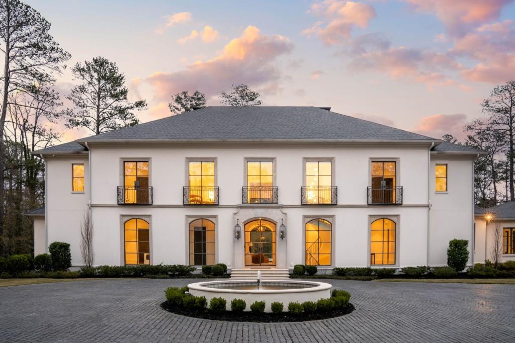 view of front of property featuring a balcony, stucco siding, and curved driveway