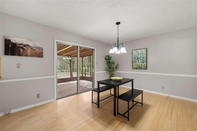 dining room featuring baseboards, a textured ceiling, an inviting chandelier, and wood finished floors